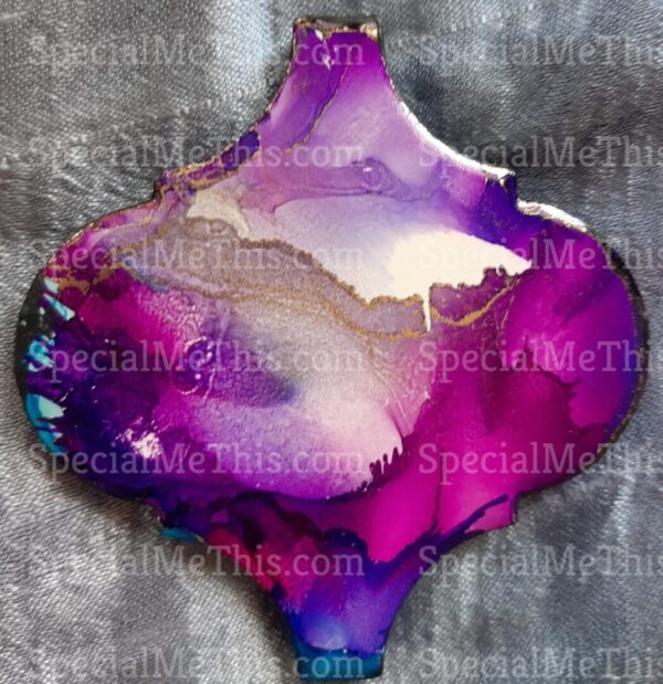 A purple and gold Arabesque Magnets pendant on a blue background.