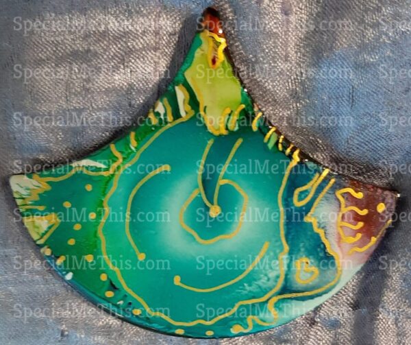 A green and yellow fish shaped cookie on top of cloth.