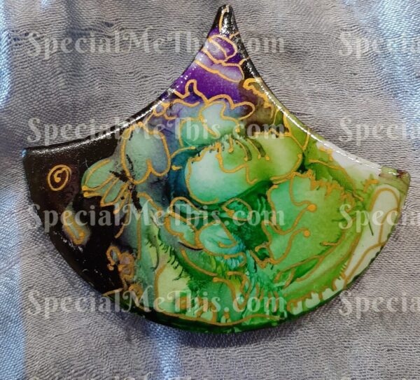 A pendant with a green and purple design on it.