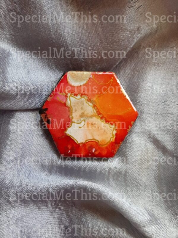 A red and yellow hexagonal shaped object on top of a silver cloth.
