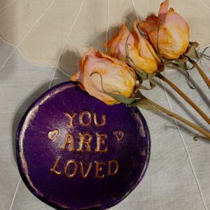 A purple plate with the words " you are loved " on it.
